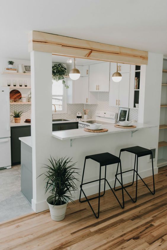 a neutral mid-century modern U-shaped kitchen with penny tiles, a wooden beam and lots of potted greenery