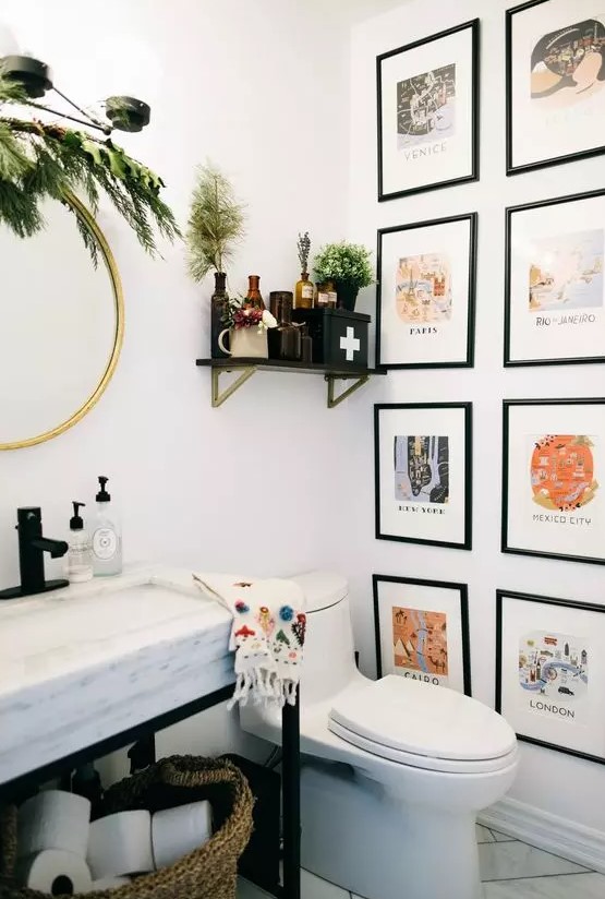 a pretty and lovely bathroom with a colorful gallery wall, a sink on a metal and stone vanity, greenery and apothecary bottles