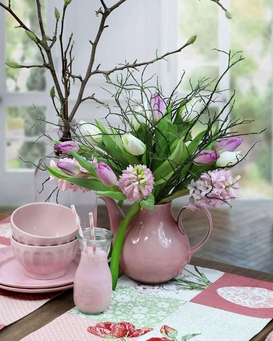 a pretty and simple spring centerpiece of a pink jug, greenerym twigs and white and pink blooms is very lovely