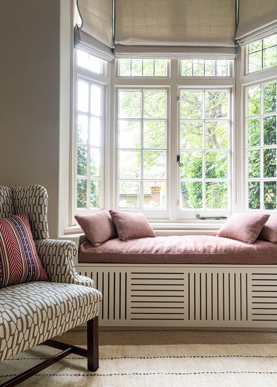 a pretty modern space with a bow window and a windowsill bench with pillows, a printed chair and printed textiles