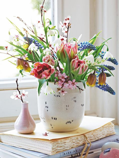 a pretty vase with colorful blooms and some leaves is a very fresh and cool spring arrangement