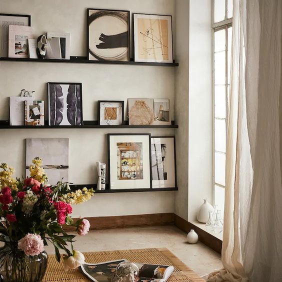 a refined gallery wall with black ledges and chic colored and black and white artworks, vases and photos is very cool and bold