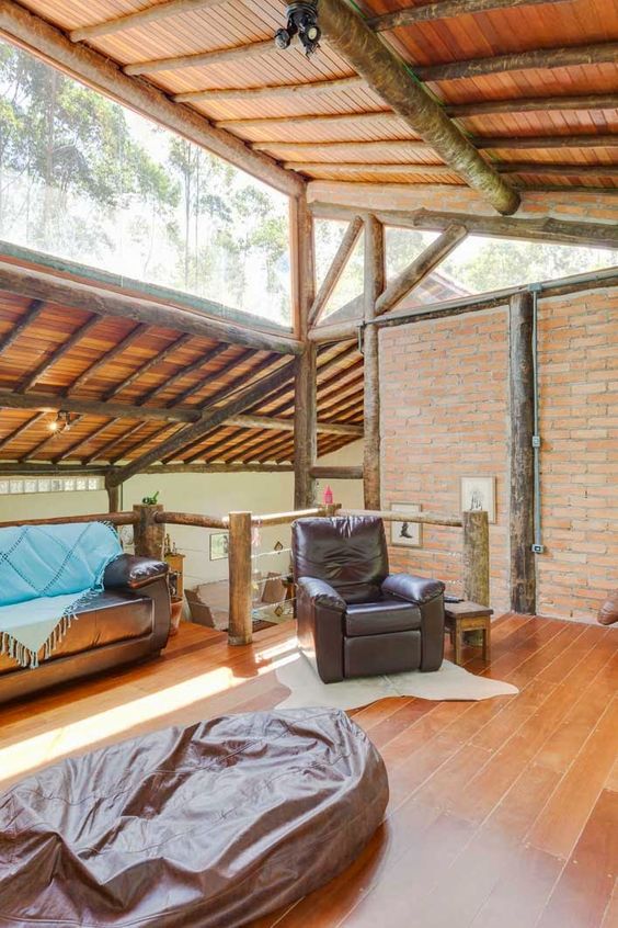 a rustic mid-century modern living room clad with brick and with rough trees, with clerestory windows that brign light in