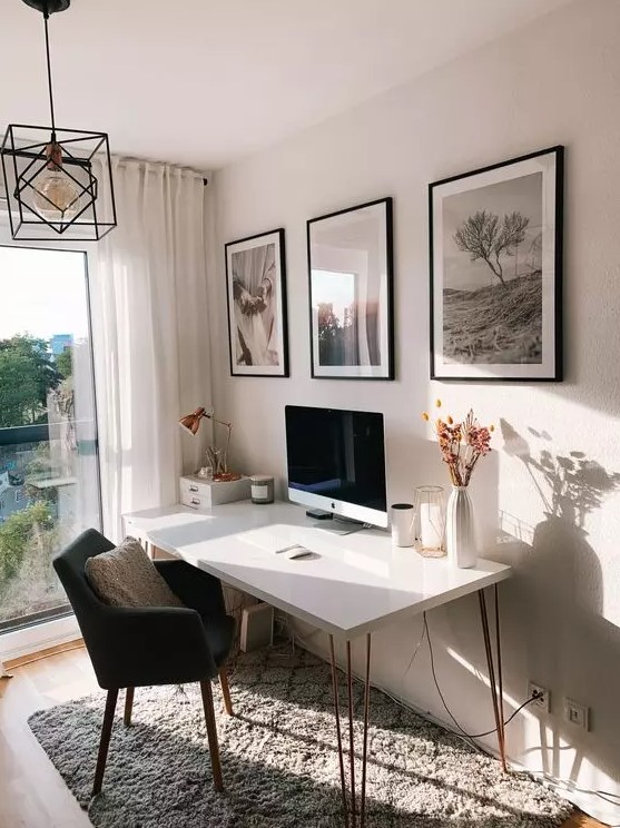 a serene Scandinavian working space with a hairpin leg desk, a black chair, a mini gallery wall and a black pendant lamp