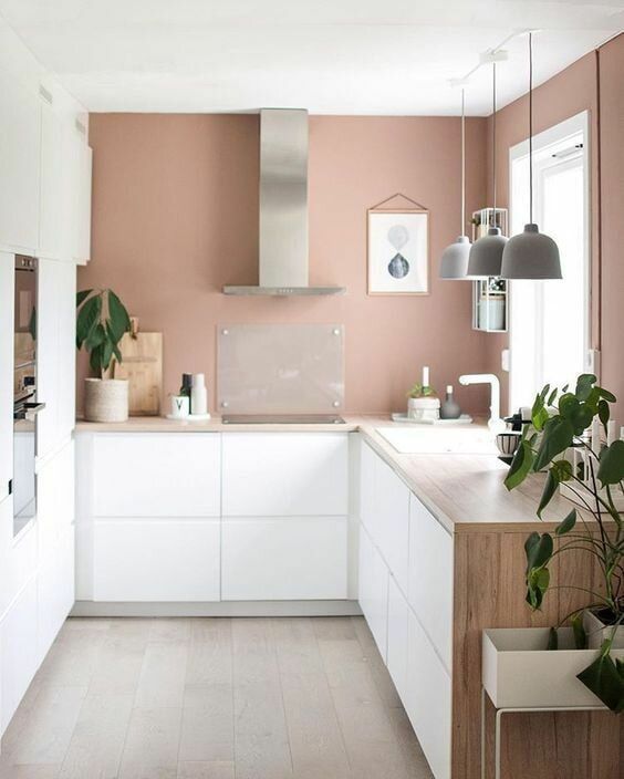 a serene kitchen with mauve walls, white minimalist cabinetry, wooden countertops, pendant lamps