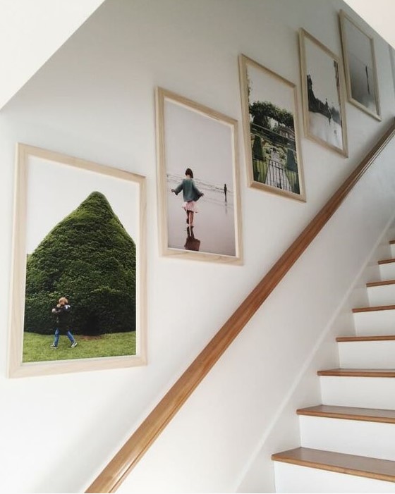 a simple and cool grid gallery wall with family photos in light-stained frames is a cool idea for a modern staircase