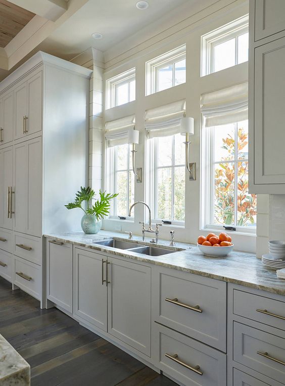 a simple white one wall kitchen with neutral stone countertops and gold handles is a beautiful and cool space