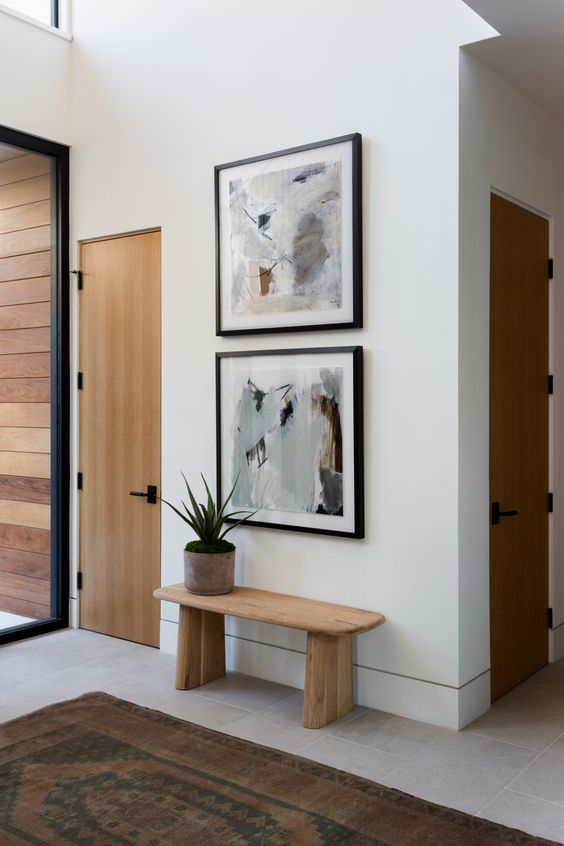 a small and chic entryway with a mini grid gallery wall, a stained bench and a potted plant