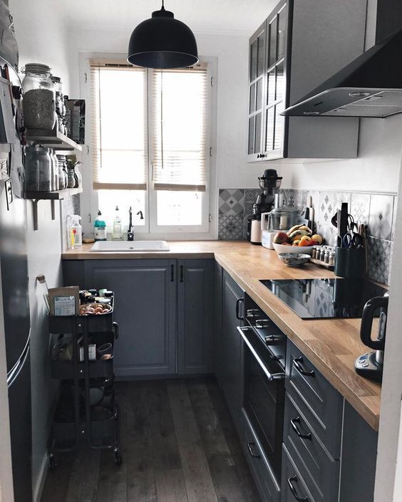 a small graphite grey L-shaped kitchen with a catchy printed backsplash and butcherblock countertops is a cool space
