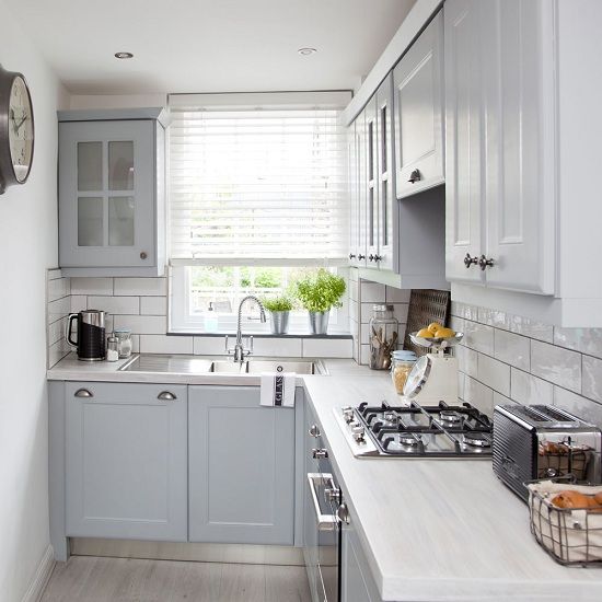 a small grey L-shaped kitchen with a white tile backsplash and white stone countertops is a pretty and welcoming space