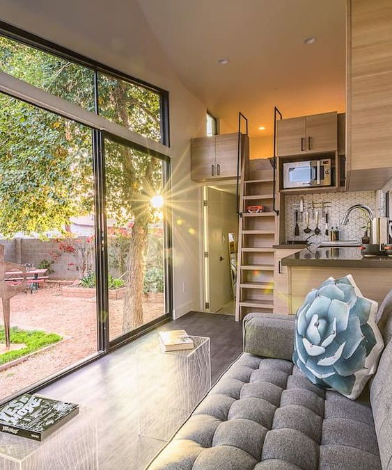 a small neutral space with a glazed wall and clerestorywindows, with modern and simple furniture and a loft bedroom