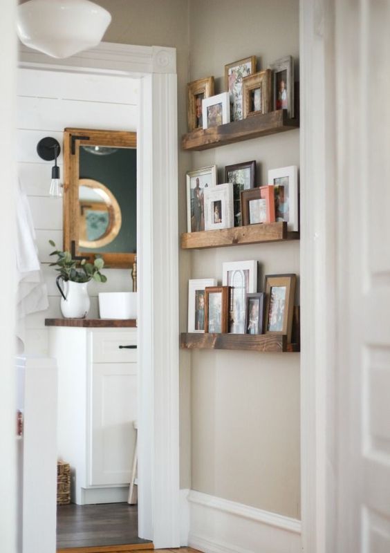 a small rustic gallery wall with stained wooden ledges and pics and artworks in wooden and colorful frames adds coziness to the space