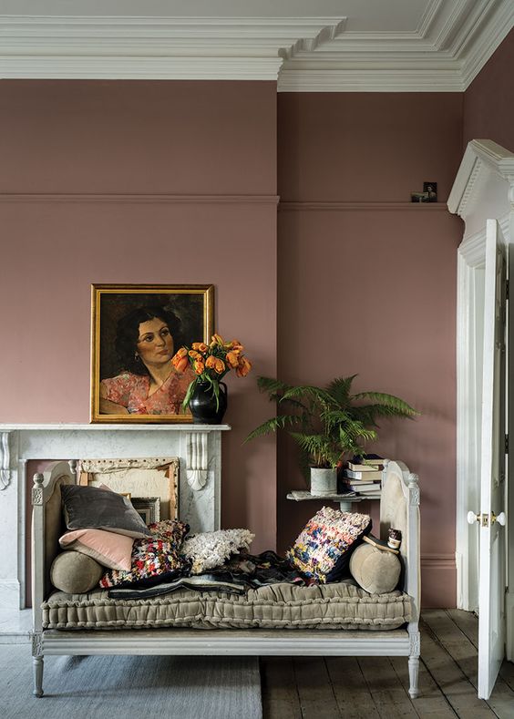 a sophisticated mauve living room with a non-working fireplace, a cool daybed and bright pillows, potted plants and a gorgeous artwork