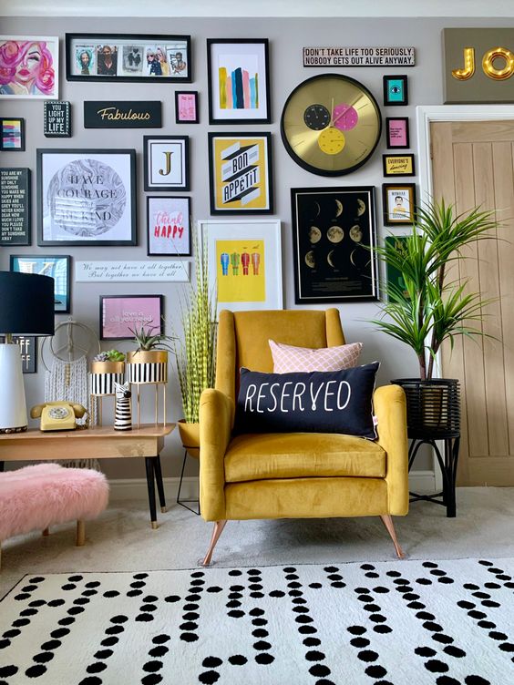 a stylish colorful gallery wall with matching black frames, colorful artworks and posters, a glam clock and bold prints