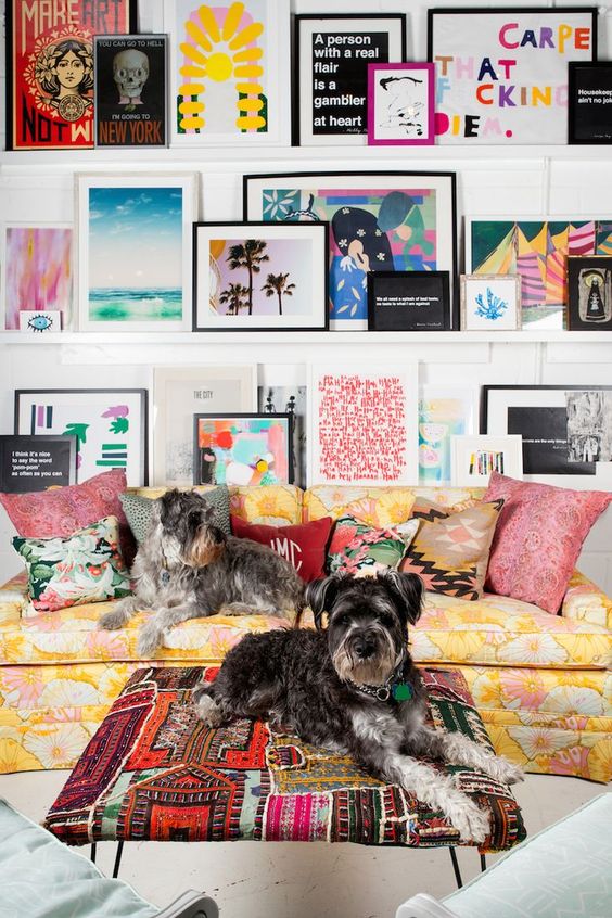 a super colorful gallery wall on ledges with bright posters, artworks, signs and even books gives personality to the space
