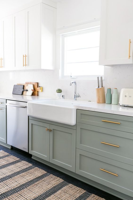 an ethereal two tone kitchen with a white backsplash and countertops, brass handles and a printed rug is super cool