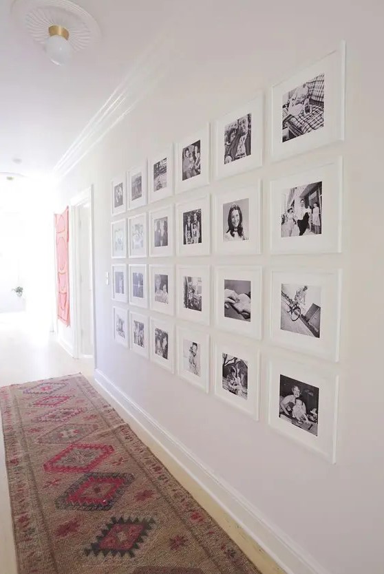an oversized black and white family gallery wall featuring white matting and frames looks very lightweight and airy