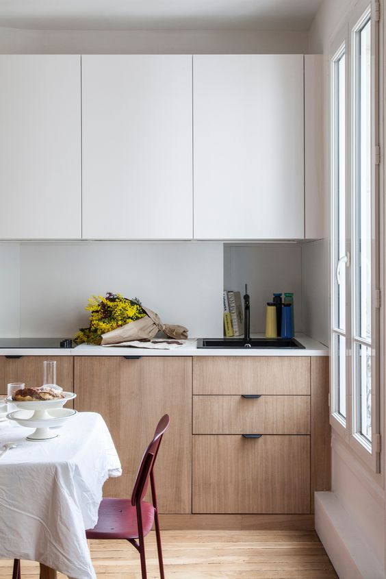 12 a minimalist two-tone kitchen with sleek cabinets, an incorporated hood and white countertops and a backsplash is chic