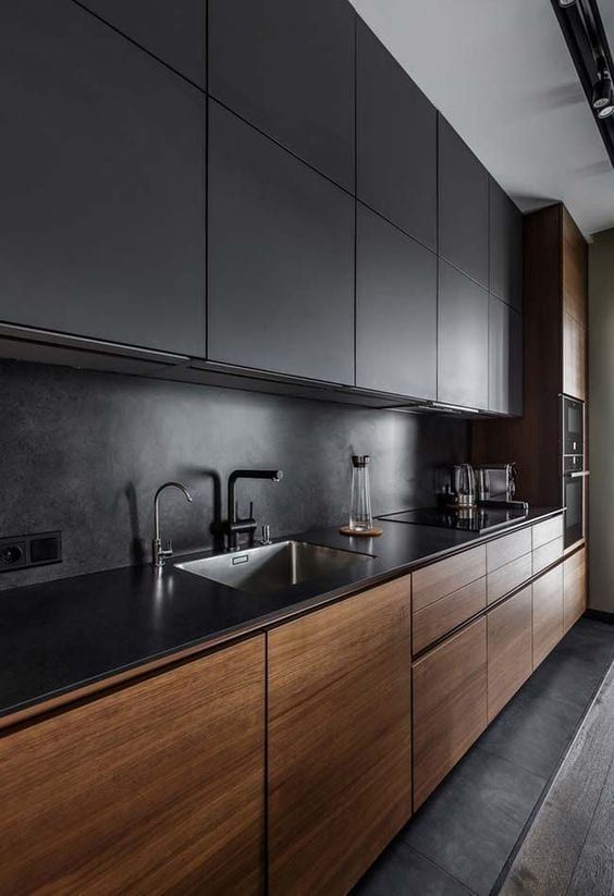 a moody minimalist kitchen with stained and black cabinets, a black countertop and a backsplash plus an integrated hood that isn't seen