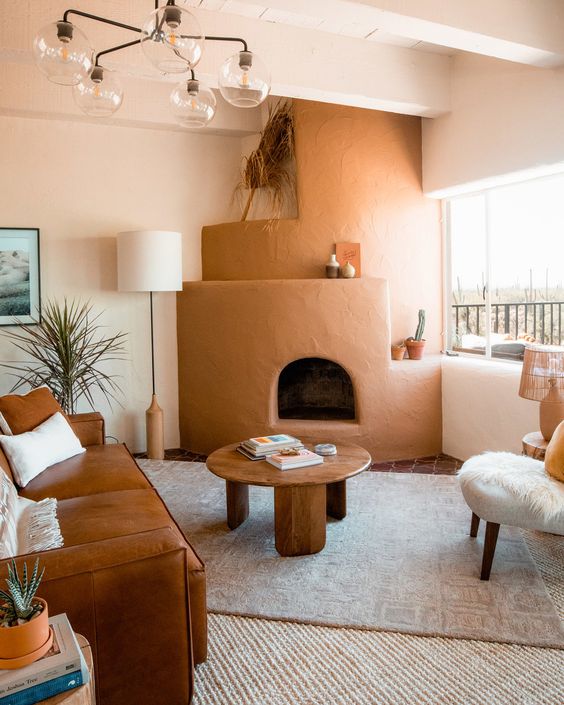 a cool earthy tone living room with a brown sofa, a brown hearth, a low table, a chic chandelier and layered rugs