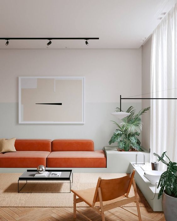 an all-neutral minimalist living room with a bold orange built-in sofa and potted plants looks vivacious and lively