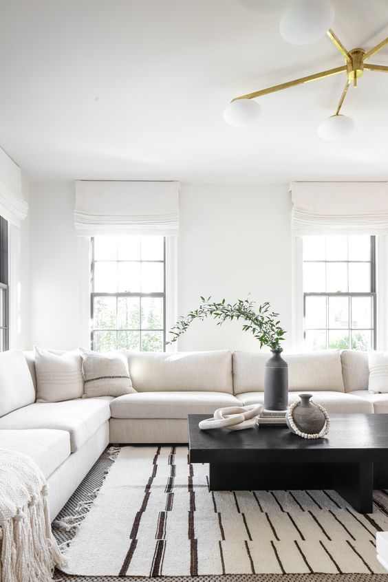 a modern black and white living room with a large sofa, a low black table, a vase with greenery and a chic chandelier