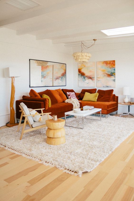 a bold living room with a rust colored sectional and a bright gallery wall plus statement lamps