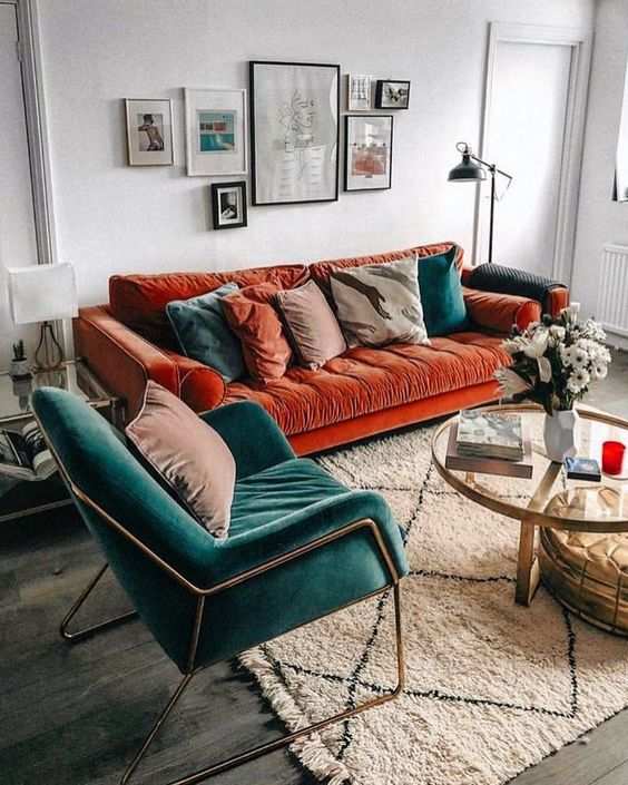 a charming living room with a bold burnt orange sofa, a teal chair and matching pillows plus a lovely gallery wall