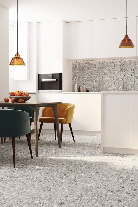 a chic modern kitchen and dining space with grey terrazzo on the floor and backsplash that brings pattern and a bit of color to the space