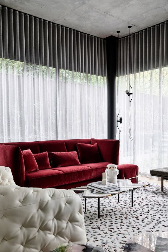 a cool monochromatic space with black and white furniture, a printed and textural rug and a bold red sofa for a touch of color