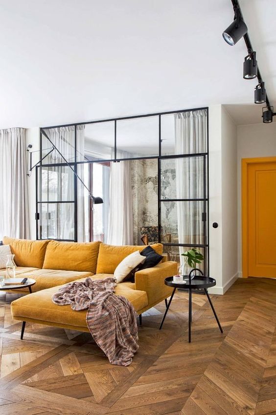 a lovely contemporary space with a warm yellow sectional, a black able and some black and white pillows