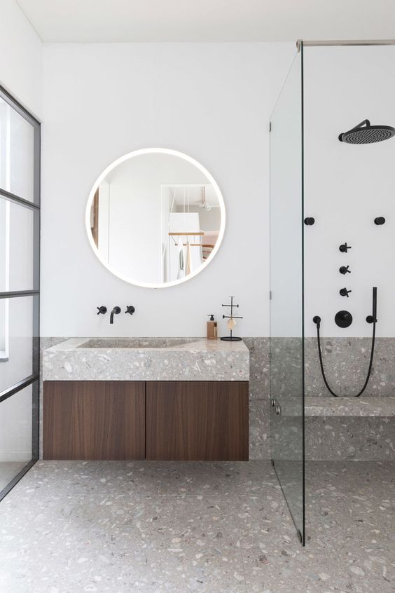 a minimalist bathroom in neutrals is made eye catchy with grey terrazzo on the floor and countertops and black fixtures