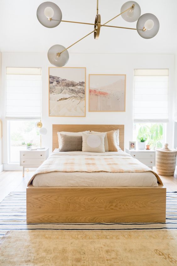 a neutral bedroom with a blonde wood bed, white nightstands, printed textiles and lovely artworks is pure chic