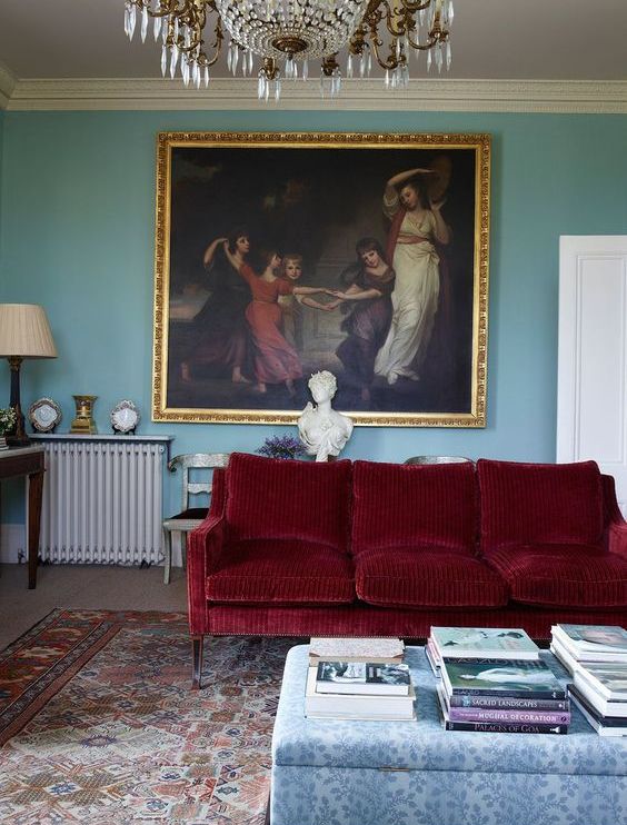 https://www.digsdigs.com/photos/2021/04/a-refined-living-room-with-blue-walls-a-deep-red-sofa-a-floral-ottoman-a-bold-vintage-artwork-and-a-crystal-chandelier.jpg