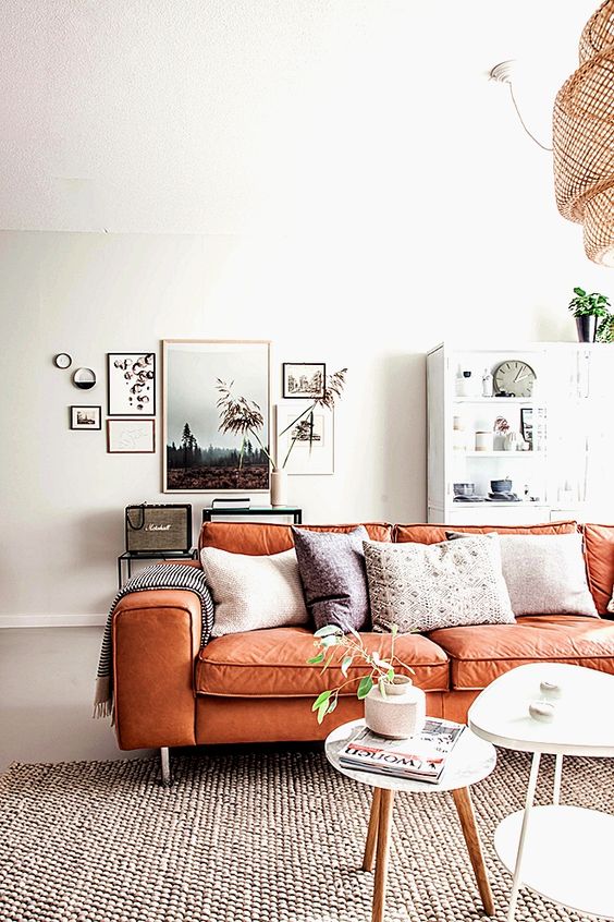 a serene Scandinavian living room with neutral furniture, a chic gallery wall and an orange leather sofa with boho pillows is amazing