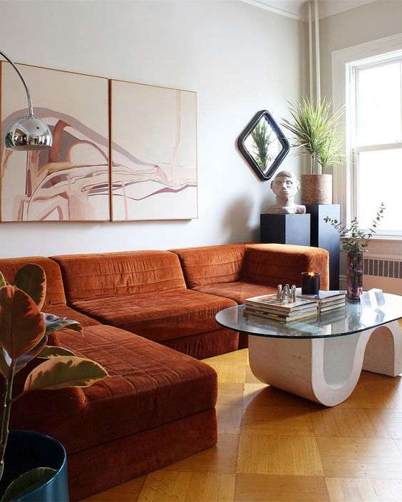 a whimsical space with a rust-colroed sectional, a quirky table, potted plants and a lovely artwork is wow