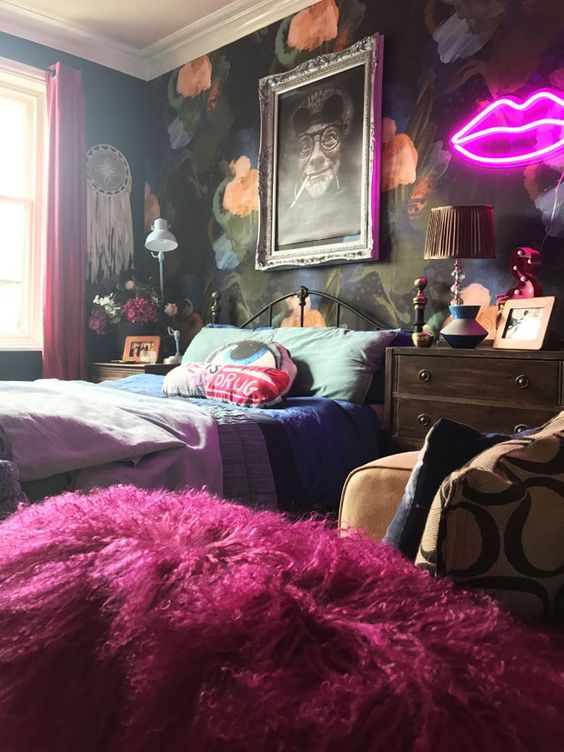 a bold maximalist bedroom with a dark floral accent wall, a metal bed, mid-century modern dressers, bold bedding and a neon light