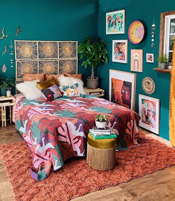 a bold maximalist bedroom with green walls, a bed with a woven headboard, colorful textiles and a bold gallery wall plus statement plants