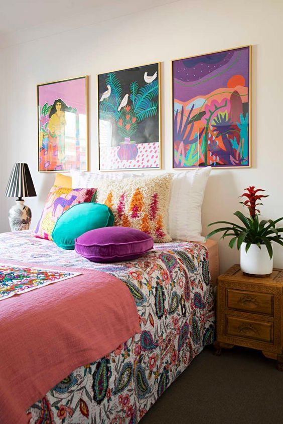 a bright maximalist bedroom with wooden furniture, a colorful gallery wall and bright textiles and bedding is amazing