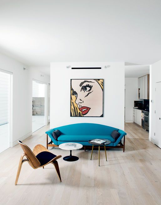 a catchy living room with much negative space, a statement artwork, a turquoise sofa, a plywood chair and tables