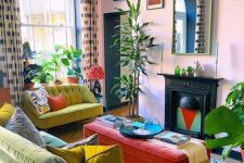 a colorful and maximalist living room with pink walls, green and mustard furniture, statement plants and bright artworks