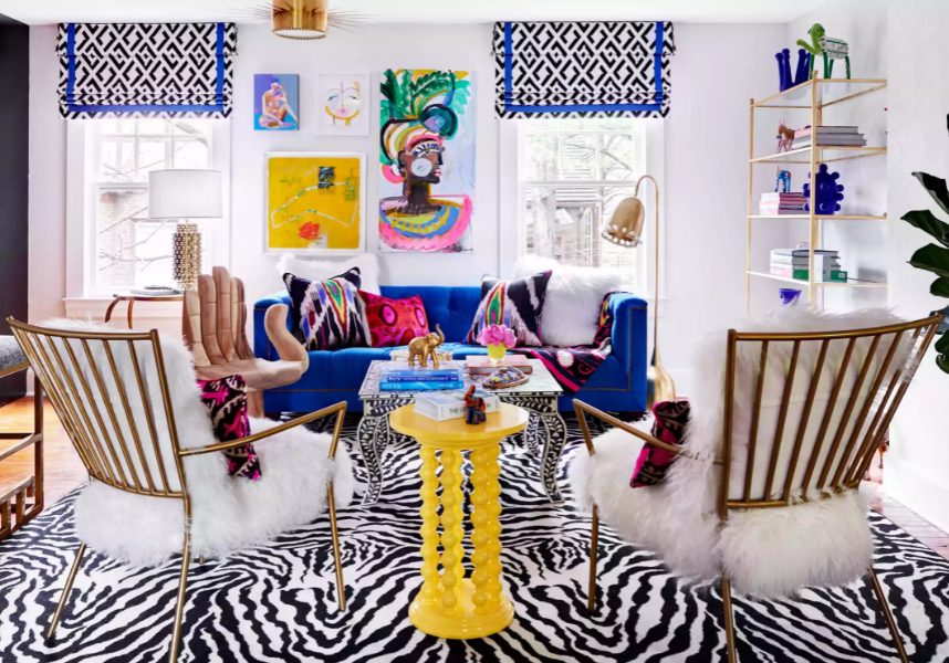 a colorful living room with a bold printed rug and curtains, an electric blue sofa and a yellow table, super bright pillows and a gallery wall
