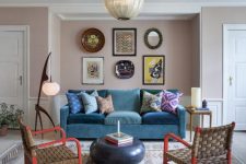 a colorful living room with blush walls, a turquoise sofa, red chairs, a bright gallery wall and catchy lamps