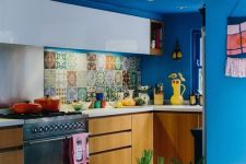 a colorful maximalist kitchen with bold blue walls and a ceiling, white and stained cabinets, white countertops and a colorful backsplash