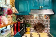 a colorful maximalist kitchen with yellow walls, teal cabinets, a bright tile backsplash, potted plants and various Asian decor