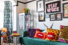 a fun maximalist living room with a green sofa and a coral ottoman, a bright gallery wall and colorful pillows plus printed textiles