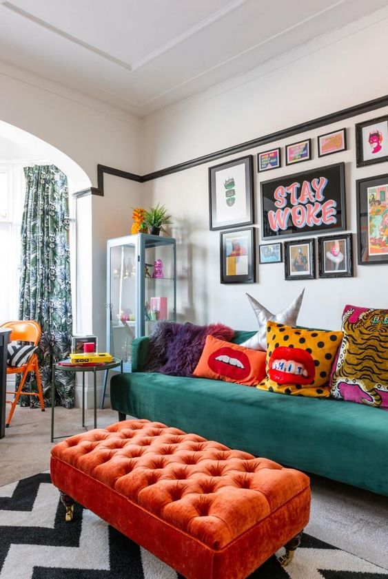 a fun maximalist living room with a green sofa and a coral ottoman, a bright gallery wall and colorful pillows plus printed textiles