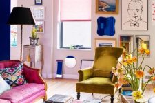 a lovely maximalist living room with blush walls, a hot pink sofa, a mustard chair, a coffee table with lots of books and a bright gallery wall