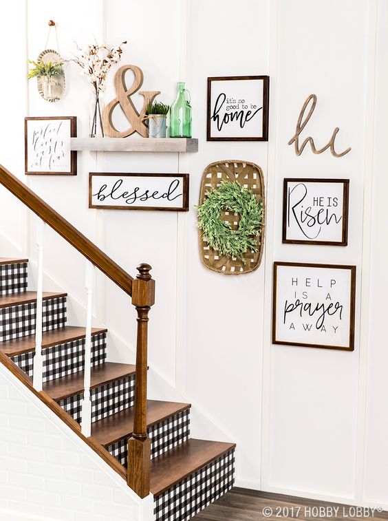 a lovely rustic gallery wall with signs in stained frames, a greenery wreath, a shelf with potted grass and an ampersand and a green bottle