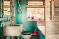 a maximalist bathroom with green walls and a hot pink ceiling, a concrete floor and a sink, copper exposed pipes and a skull